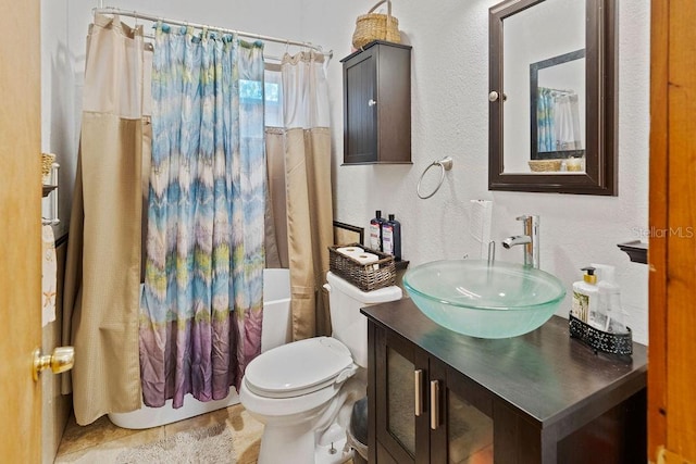 bathroom with a textured wall, shower / bathtub combination with curtain, vanity, and toilet