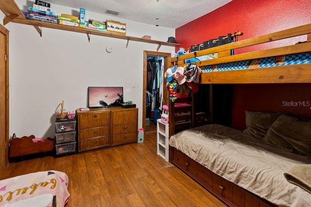 bedroom featuring wood finished floors, a walk in closet, and a closet