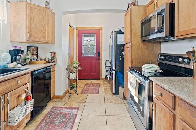 kitchen featuring stainless steel appliances, light tile patterned floors, and light brown cabinetry