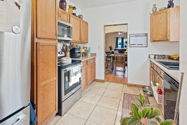 kitchen featuring stainless steel appliances, light countertops, light tile patterned floors, and a sink