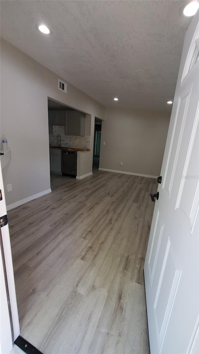 312 Dorothy Ave, Daytona Beach, FL 32117 - unfurnished living room featuring a textured ceiling, light wood-style flooring, baseboards, recessed lighting, and a sink