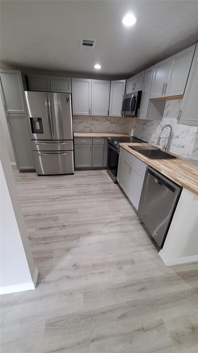 312 Dorothy Ave, Daytona Beach, FL 32117 - kitchen with stainless steel appliances, light wood finished floors, a sink, gray cabinetry, and tasteful backsplash