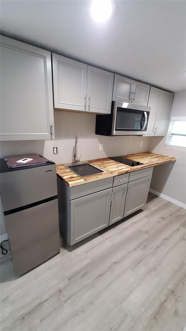 312 Dorothy Ave, Daytona Beach, FL 32117 - kitchen with appliances with stainless steel finishes, wood counters, a sink, gray cabinets, and light wood-style flooring