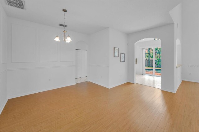 3002 Savannah Oaks Cir, Tarpon Springs, FL 34688 - empty room featuring arched walkways, light wood-style flooring, a chandelier, and baseboards