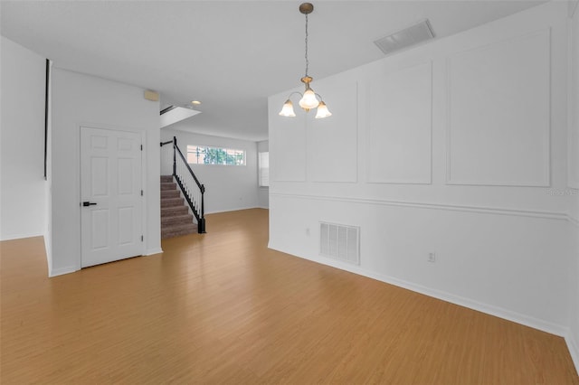 3002 Savannah Oaks Cir, Tarpon Springs, FL 34688 - spare room featuring light wood-style flooring, stairway, baseboards, and a chandelier