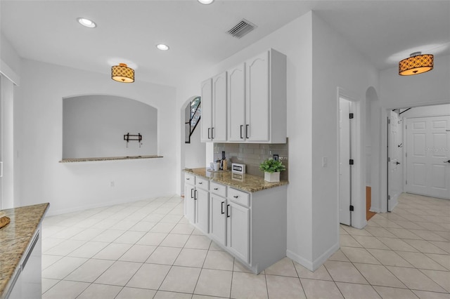 3002 Savannah Oaks Cir, Tarpon Springs, FL 34688 - kitchen featuring arched walkways, white cabinetry, light stone countertops, backsplash, and light tile patterned floors