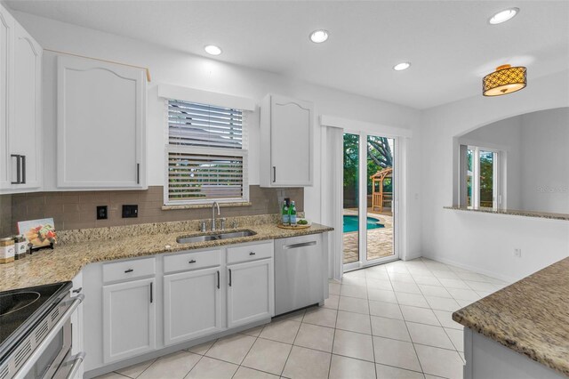 3002 Savannah Oaks Cir, Tarpon Springs, FL 34688 - kitchen with a sink, stainless steel dishwasher, decorative backsplash, white cabinetry, and light tile patterned floors