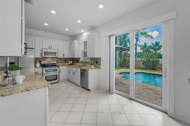 3002 Savannah Oaks Cir, Tarpon Springs, FL 34688 - kitchen featuring stainless steel appliances, a sink, recessed lighting, light stone countertops, and tasteful backsplash