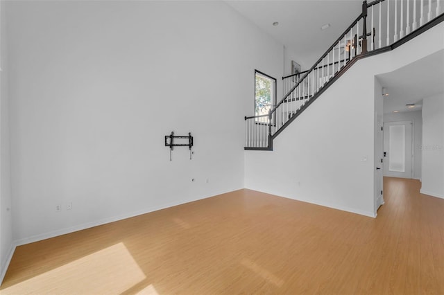 3002 Savannah Oaks Cir, Tarpon Springs, FL 34688 - unfurnished living room featuring wood finished floors, stairs, a towering ceiling, and baseboards