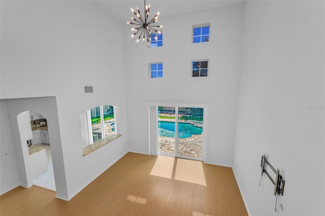3002 Savannah Oaks Cir, Tarpon Springs, FL 34688 - foyer entrance with a chandelier, a high ceiling, wood finished floors, baseboards, and arched walkways