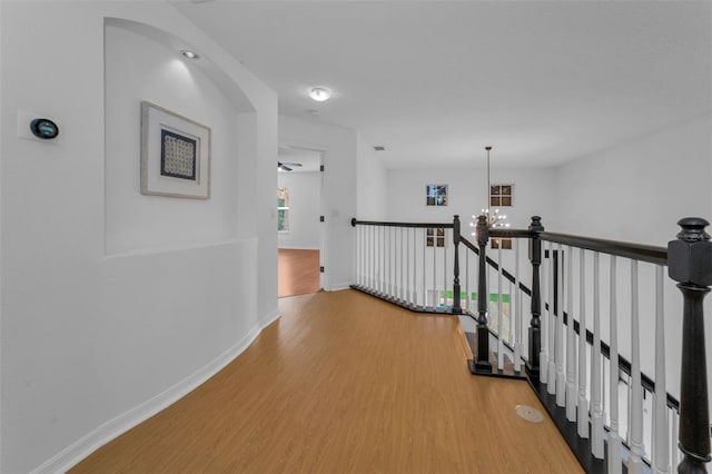 3002 Savannah Oaks Cir, Tarpon Springs, FL 34688 - hallway featuring light wood-style flooring, an upstairs landing, a chandelier, and baseboards