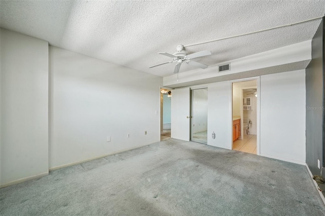 6020 S Shore Blvd Unit 709, Gulfport, FL 33707 - unfurnished bedroom featuring light colored carpet, a textured ceiling, ensuite bath, and ceiling fan