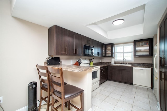 12300 Park Blvd Unit 222, Seminole, FL 33772 - kitchen with white appliances, a sink, glass insert cabinets, dark brown cabinets, and a peninsula