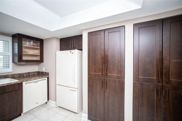 12300 Park Blvd Unit 222, Seminole, FL 33772 - kitchen featuring white appliances, light tile patterned floors, dark brown cabinetry, glass insert cabinets, and dark countertops