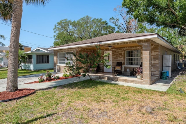 314 Bath St, Tarpon Springs, FL 34689 - view of front of property with a ceiling fan, a front lawn, brick siding, a patio area, and roof with shingles