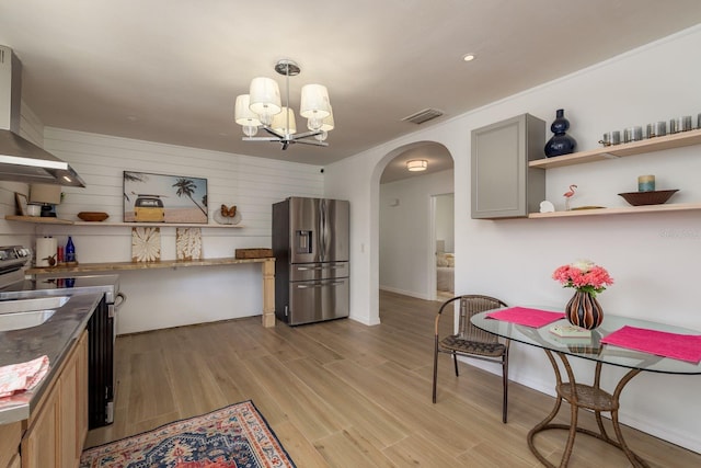 314 Bath St, Tarpon Springs, FL 34689 - kitchen featuring stainless steel fridge with ice dispenser, open shelves, wall chimney exhaust hood, arched walkways, and light wood-type flooring