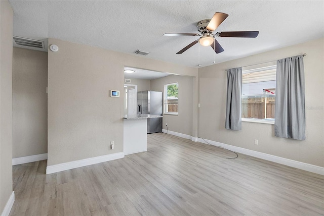 1310 43rd St S, Saint Petersburg, FL 33711 - unfurnished living room featuring ceiling fan, light wood-type flooring, baseboards, and a textured ceiling