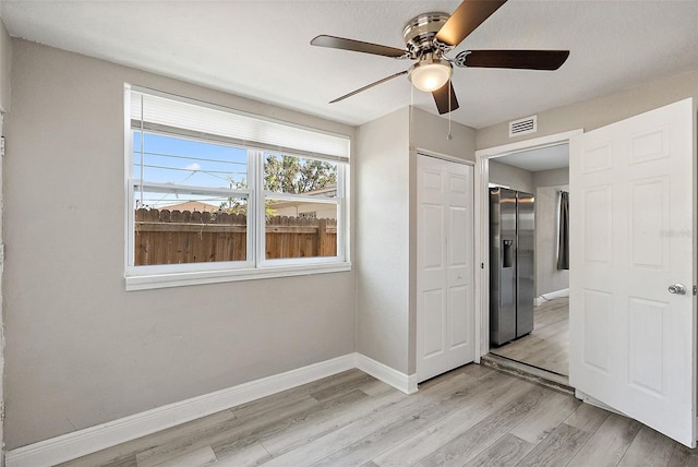 1310 43rd St S, Saint Petersburg, FL 33711 - unfurnished bedroom with baseboards, light wood-style flooring, stainless steel fridge, a closet, and ceiling fan