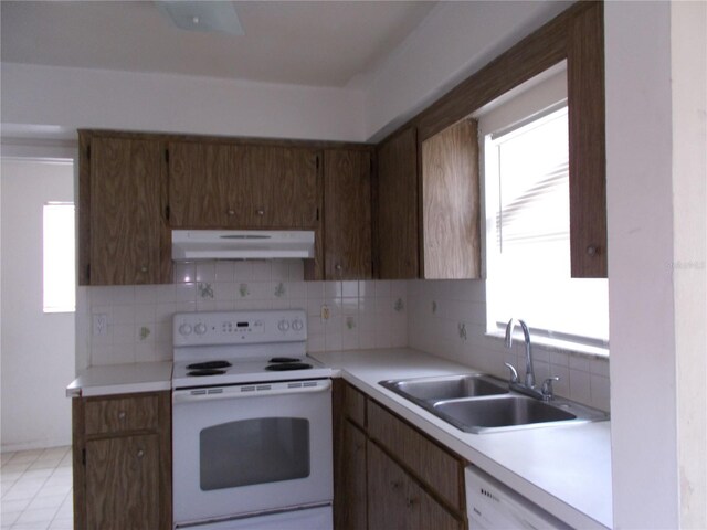 kitchen with white appliances, under cabinet range hood, a sink, and tasteful backsplash