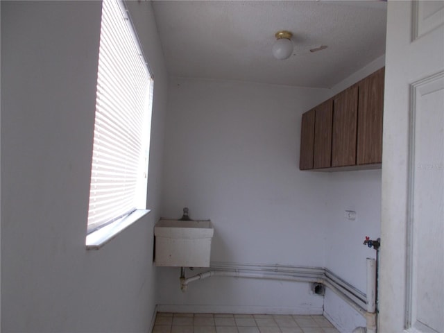 clothes washing area with cabinet space and light tile patterned floors
