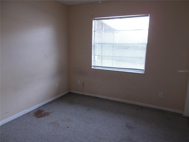 carpeted empty room featuring baseboards