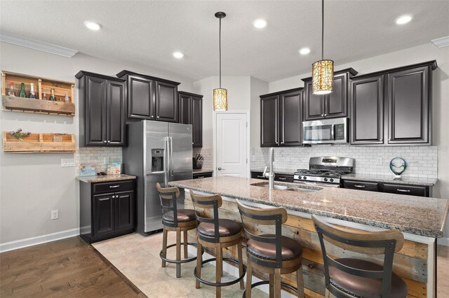 4264 Bexley Village Dr, Land O Lakes, FL 34638 - kitchen featuring stainless steel appliances, a sink, decorative backsplash, an island with sink, and light stone countertops