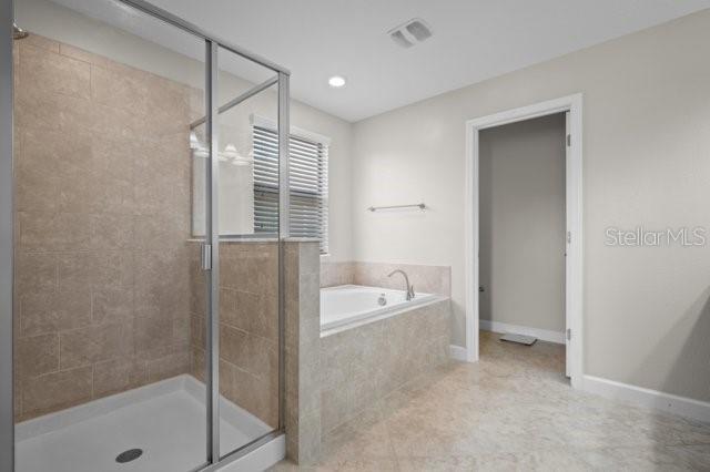 4264 Bexley Village Dr, Land O Lakes, FL 34638 - bathroom with a shower stall, a garden tub, baseboards, and tile patterned floors