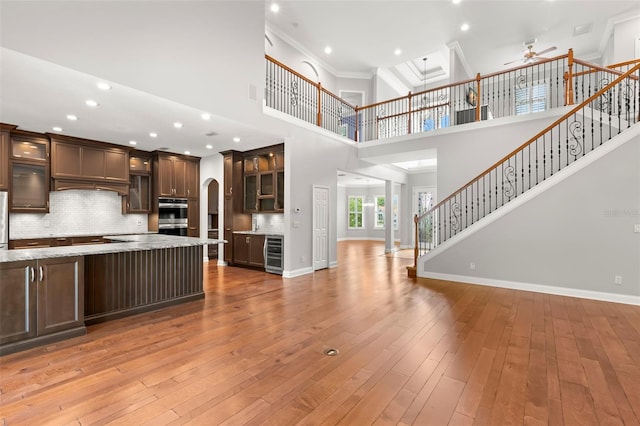 1171 Red Maple Cir NE, Saint Petersburg, FL 33703 - kitchen with wine cooler, open floor plan, a ceiling fan, dark brown cabinets, and a towering ceiling