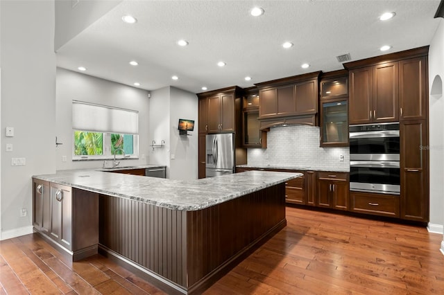 1171 Red Maple Cir NE, Saint Petersburg, FL 33703 - kitchen featuring stainless steel appliances, a sink, backsplash, wood-type flooring, and a peninsula