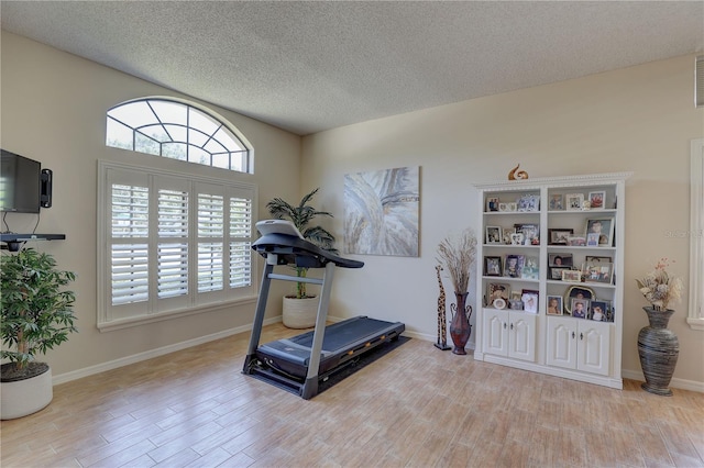 3338 Laurelwood Ct, Tarpon Springs, FL 34688 - exercise area with light wood-style flooring, a textured ceiling, and baseboards