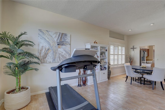 3338 Laurelwood Ct, Tarpon Springs, FL 34688 - exercise area featuring light wood finished floors, baseboards, and a textured ceiling