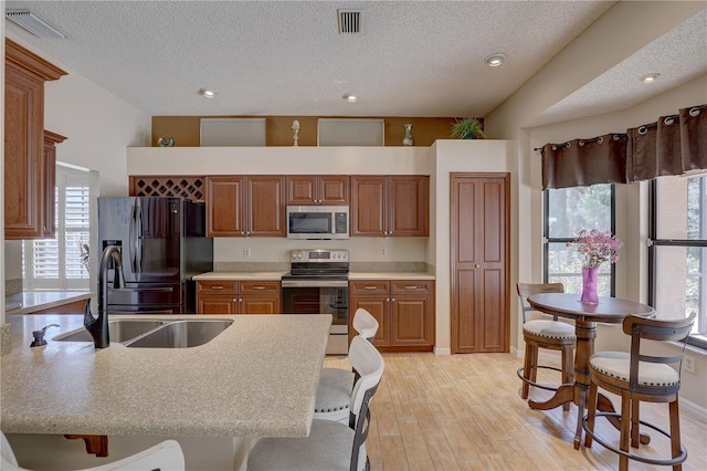 3338 Laurelwood Ct, Tarpon Springs, FL 34688 - kitchen featuring stainless steel appliances, a sink, a peninsula, a textured ceiling, and a kitchen breakfast bar