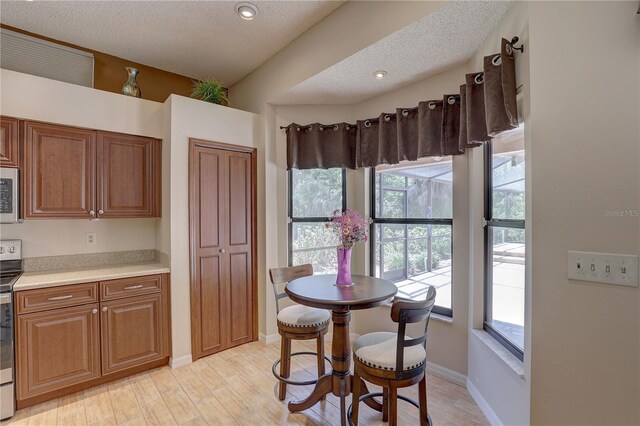 3338 Laurelwood Ct, Tarpon Springs, FL 34688 - kitchen with light countertops, a textured ceiling, brown cabinets, light wood-style flooring, and stainless steel electric range