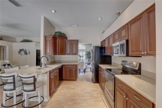 3338 Laurelwood Ct, Tarpon Springs, FL 34688 - kitchen with stainless steel appliances, a sink, a peninsula, a kitchen breakfast bar, and light wood-style flooring