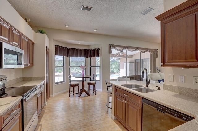 3338 Laurelwood Ct, Tarpon Springs, FL 34688 - kitchen featuring stainless steel appliances, a sink, light countertops, a textured ceiling, and light wood finished floors
