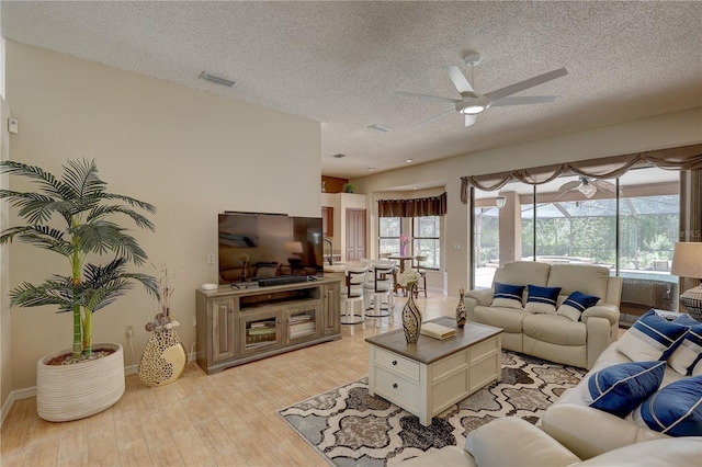 3338 Laurelwood Ct, Tarpon Springs, FL 34688 - living room featuring a ceiling fan, a textured ceiling, light wood-style flooring, and baseboards