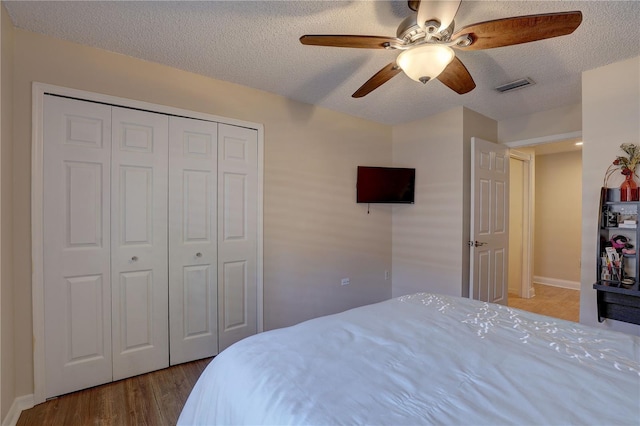 3338 Laurelwood Ct, Tarpon Springs, FL 34688 - bedroom with a closet, a textured ceiling, wood finished floors, a ceiling fan, and baseboards