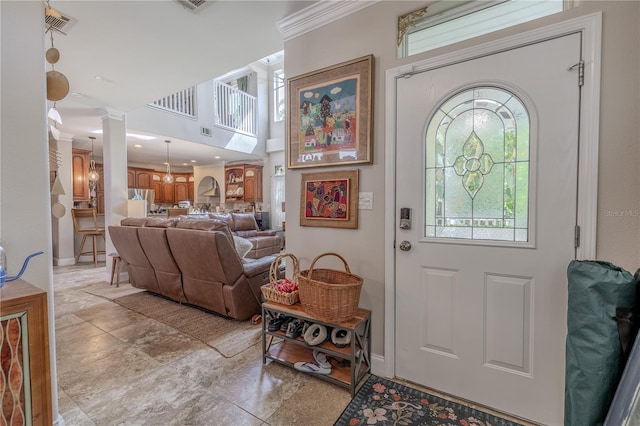foyer entrance featuring decorative columns, baseboards, and ornamental molding