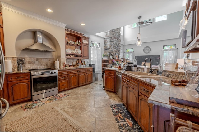 kitchen with appliances with stainless steel finishes, wall chimney exhaust hood, a sink, backsplash, and recessed lighting