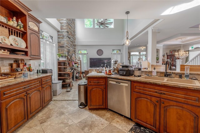 kitchen with stainless steel dishwasher, a sink, healthy amount of natural light, decorative light fixtures, and a towering ceiling