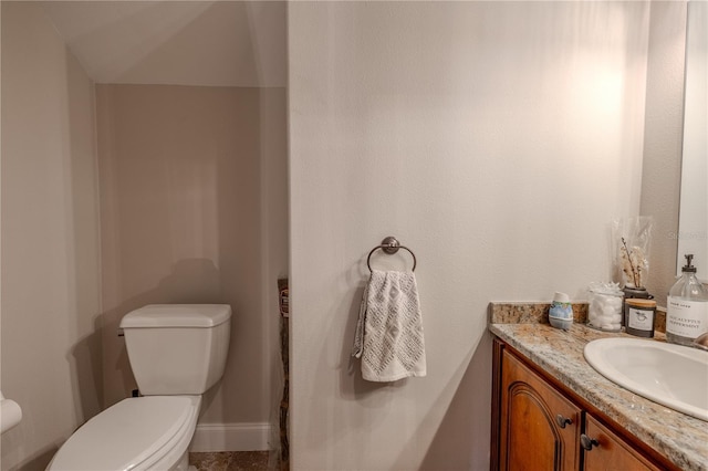 half bath with toilet, vanity, and baseboards