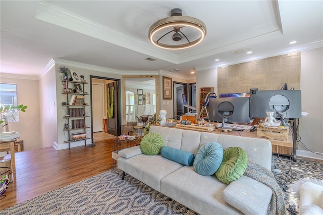 living area with crown molding, wood finished floors, a tray ceiling, baseboards, and recessed lighting