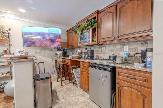 kitchen featuring refrigerator, ornamental molding, brown cabinets, decorative backsplash, and light stone countertops