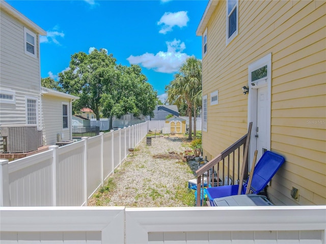 fenced backyard with central AC unit, entry steps, and a residential view
