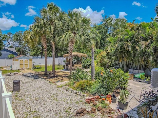 fenced backyard featuring a shed, a patio area, an outbuilding, and central AC