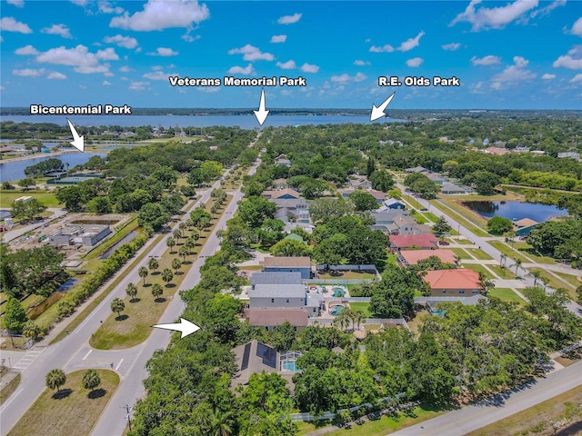aerial view of residential area with a nearby body of water and a tree filled landscape
