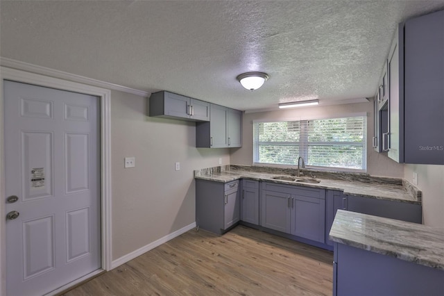 2112 33rd St SE, Ruskin, FL 33570 - kitchen featuring a sink, light wood finished floors, gray cabinets, a textured ceiling, and light stone countertops