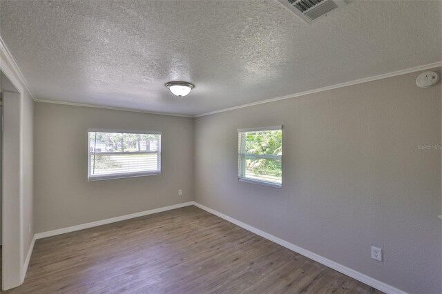 2112 33rd St SE, Ruskin, FL 33570 - spare room featuring healthy amount of natural light, a textured ceiling, wood finished floors, ornamental molding, and baseboards