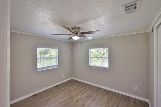 2112 33rd St SE, Ruskin, FL 33570 - unfurnished room featuring healthy amount of natural light, wood finished floors, baseboards, a textured ceiling, and crown molding