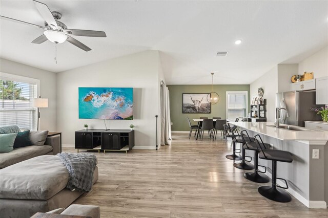 living area featuring light wood-style floors, baseboards, a ceiling fan, vaulted ceiling, and recessed lighting